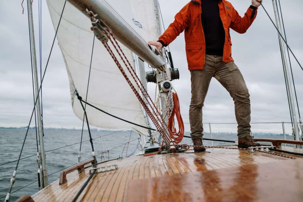 Man in Red Jacket and Brown Pants Standing on Brown Wooden Dock