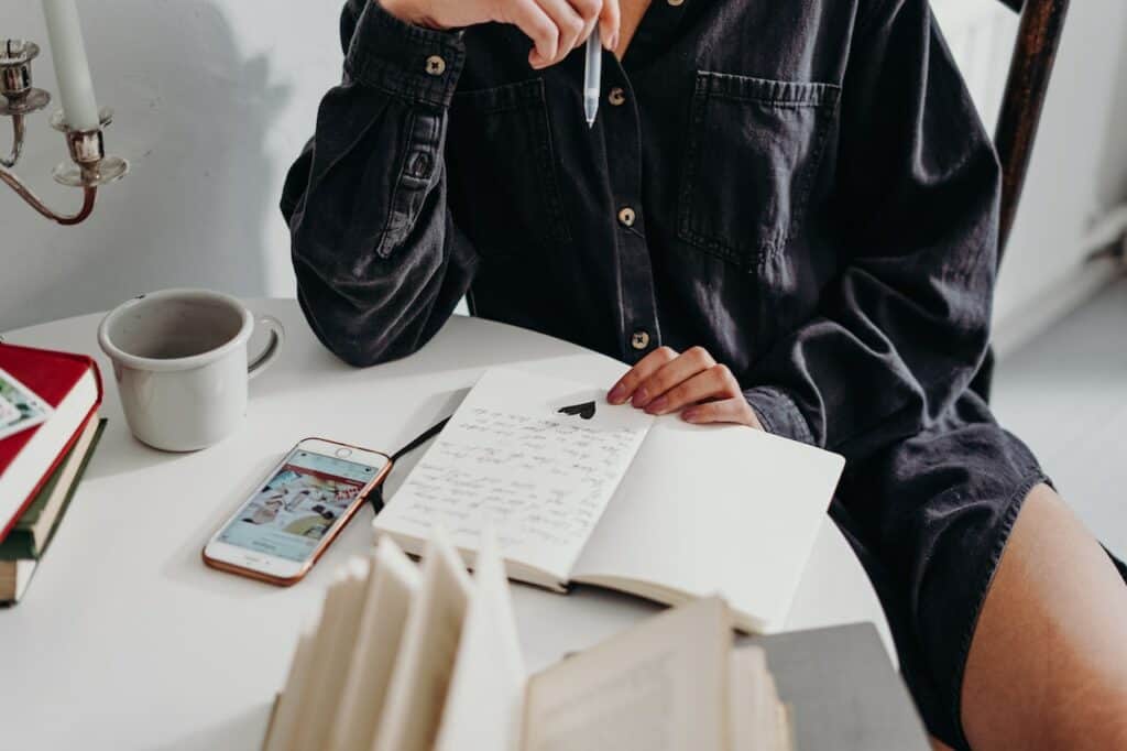 person sitting at a coffee table, writing on a notebook