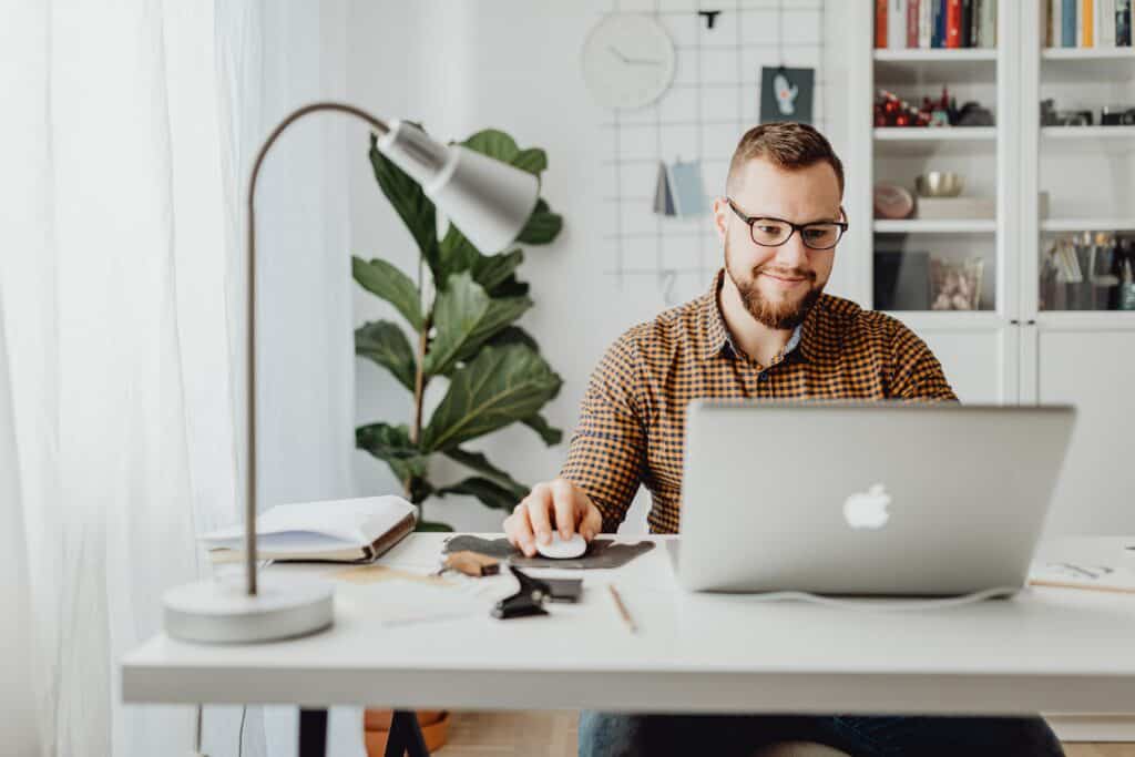 a man smiling while writing on his macbook