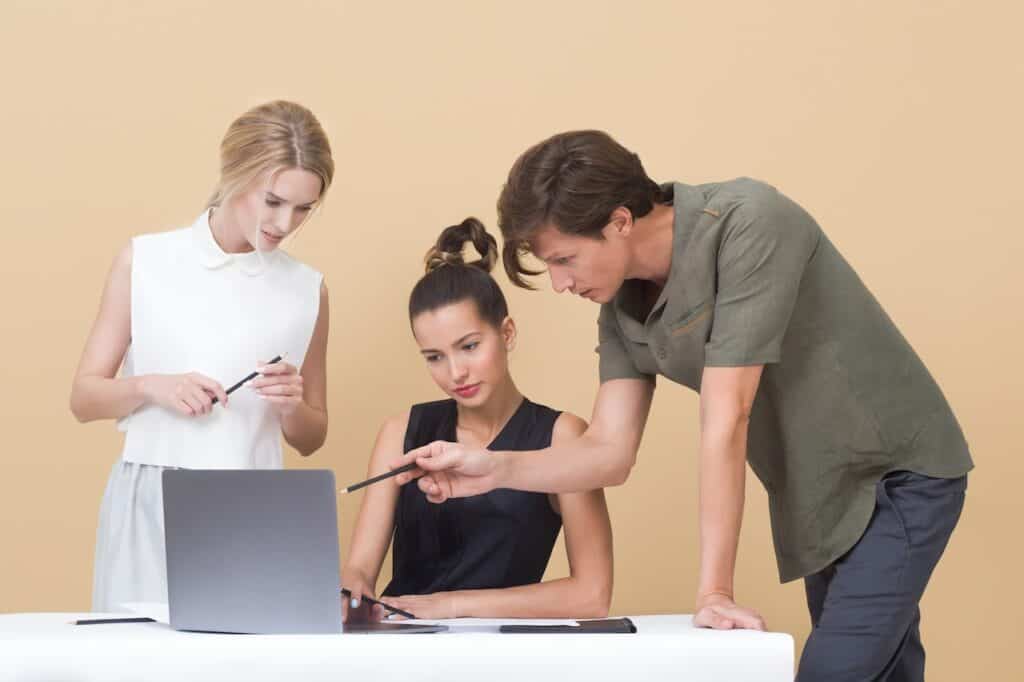 three people talking in front of a laptop