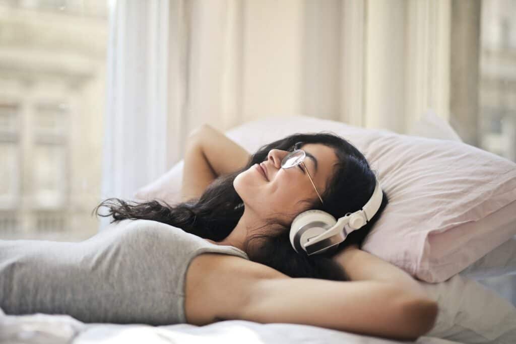 Woman in Gray Tank Top Lying on Bed listening to audiobooks